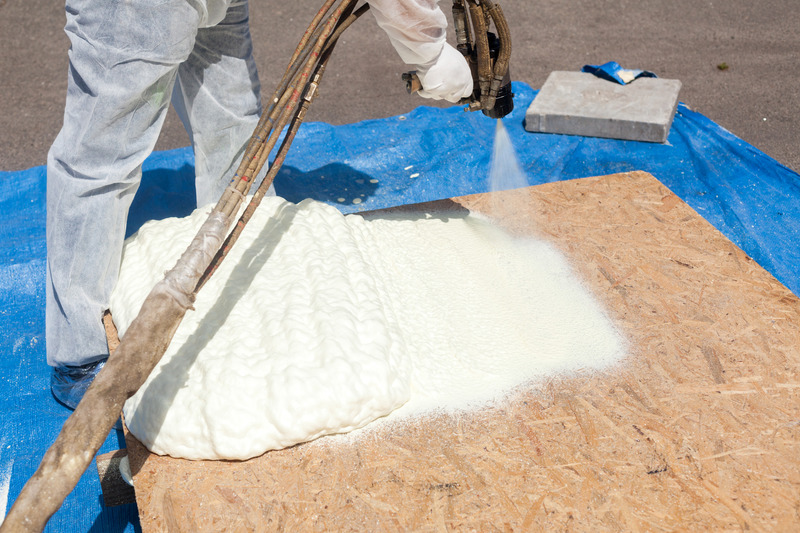 Technician spraying foam insulation using Plural Component Spray Gun. Spraying polyurethane foam for roof